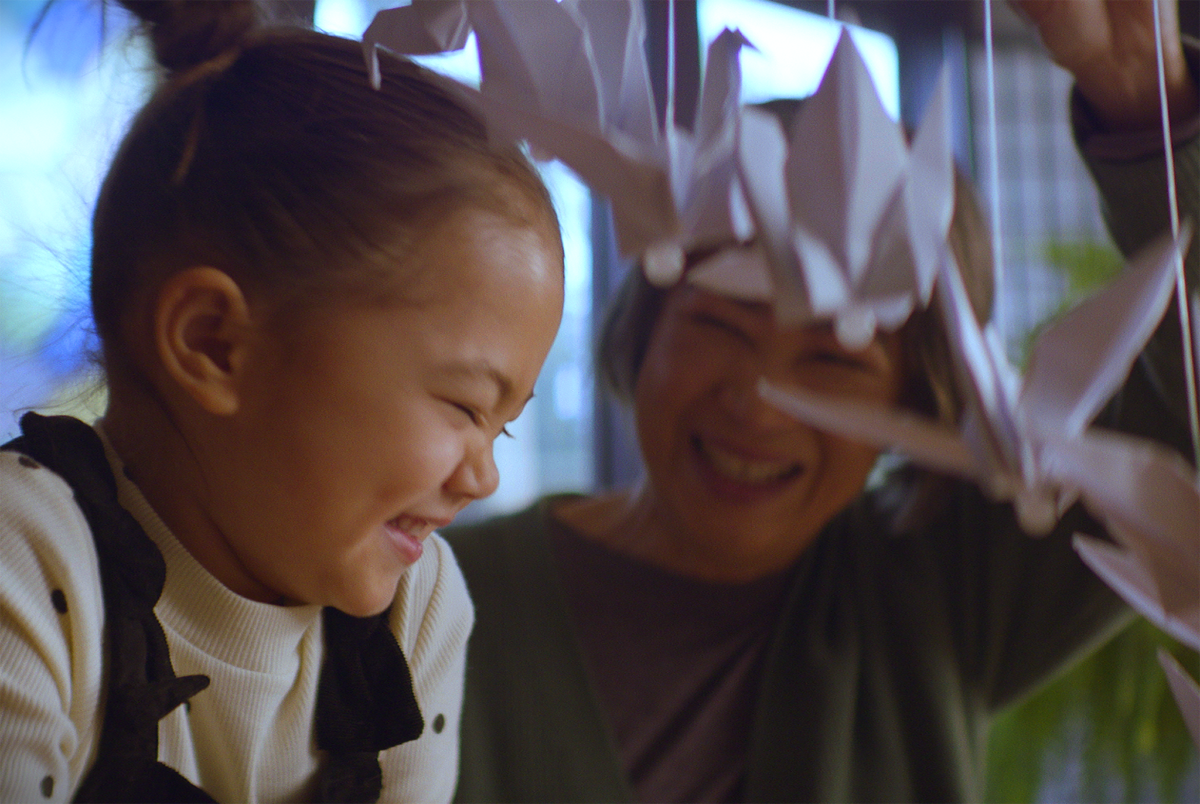 A woman and a girl playing with origami paper and both smiling